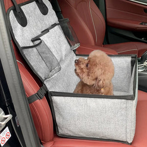 Petit caniche assis dans un siège auto pour chien fixé sur le siège passager