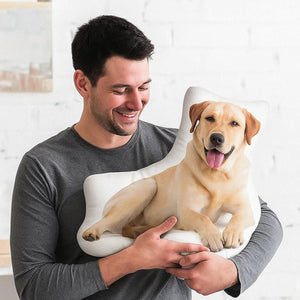 Homme souriant qui tient contre lui un coussin découpé à la forme d'un labrador