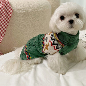 Petit chien blanc portant le pull de Noël vert à col roulé motif pain d'épice